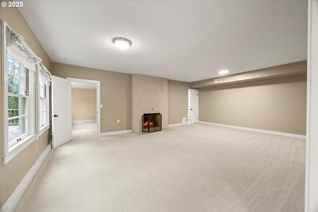 interior space with a large fireplace, light colored carpet, and baseboards