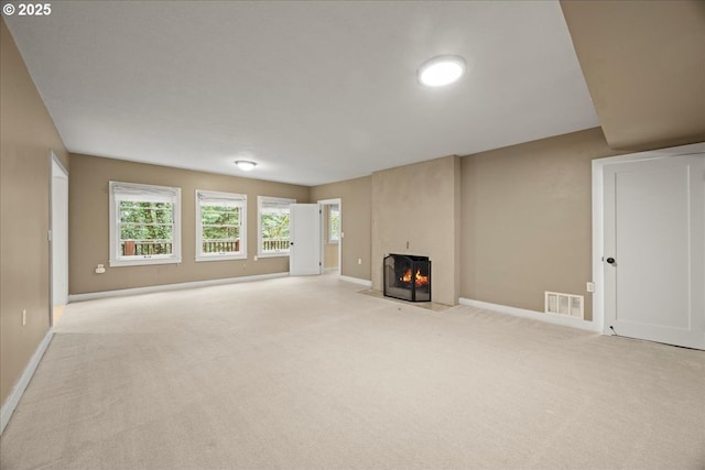 unfurnished living room with a large fireplace, carpet floors, visible vents, and baseboards