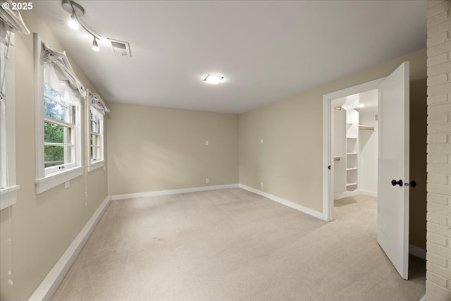 spare room with baseboards and light colored carpet