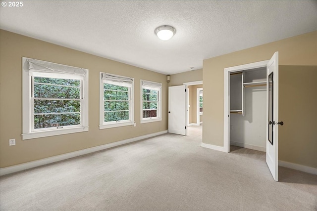 unfurnished bedroom featuring a textured ceiling, a closet, carpet flooring, and baseboards