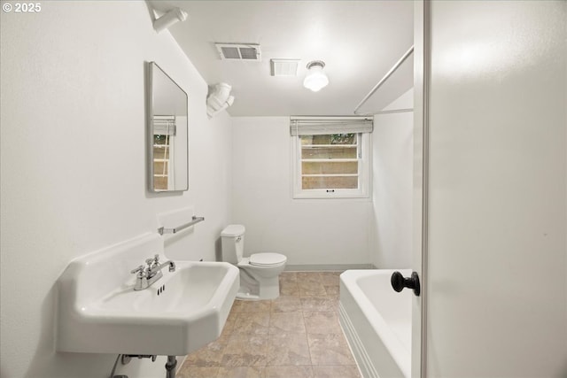 bathroom with toilet, a sink, a bathing tub, and visible vents