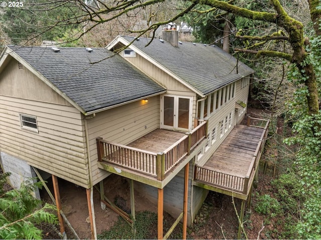 rear view of house with a shingled roof, a chimney, and a wooden deck