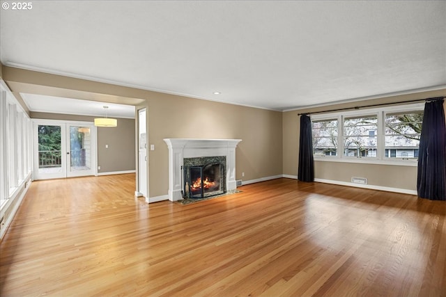 unfurnished living room featuring light wood-type flooring, a high end fireplace, and a healthy amount of sunlight