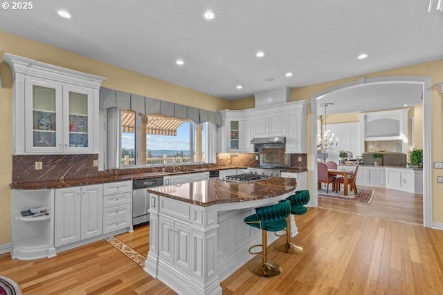 9337 SE Pennington Ct, Happy Valley, OR 97086 - kitchen with appliances with stainless steel finishes, arched walkways, white cabinets, a breakfast bar area, and light wood finished floors