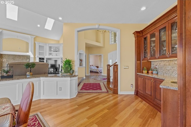 9337 SE Pennington Ct, Happy Valley, OR 97086 - kitchen featuring decorative backsplash, open floor plan, glass insert cabinets, light wood finished floors, and lofted ceiling