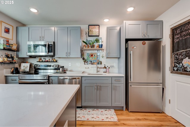 kitchen featuring stainless steel appliances, gray cabinets, light hardwood / wood-style floors, and sink