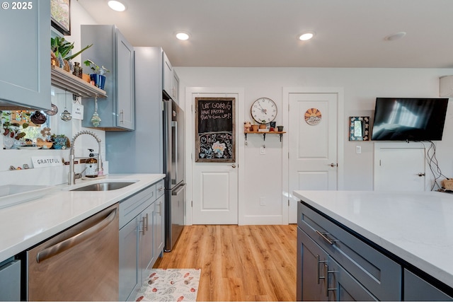 kitchen with appliances with stainless steel finishes, light hardwood / wood-style flooring, and sink