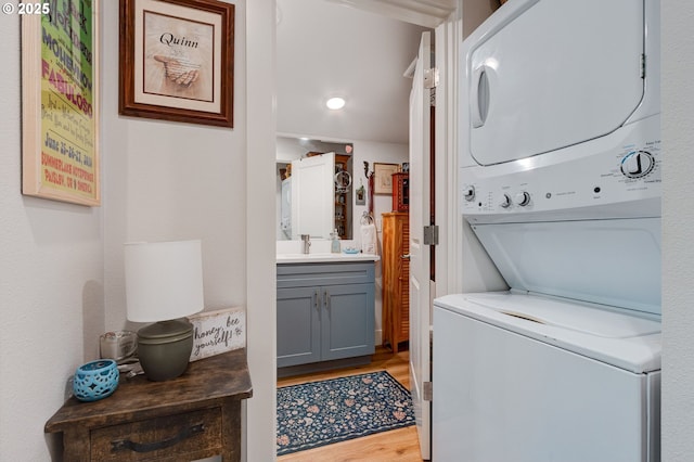 laundry room featuring sink, light hardwood / wood-style flooring, and stacked washer and dryer