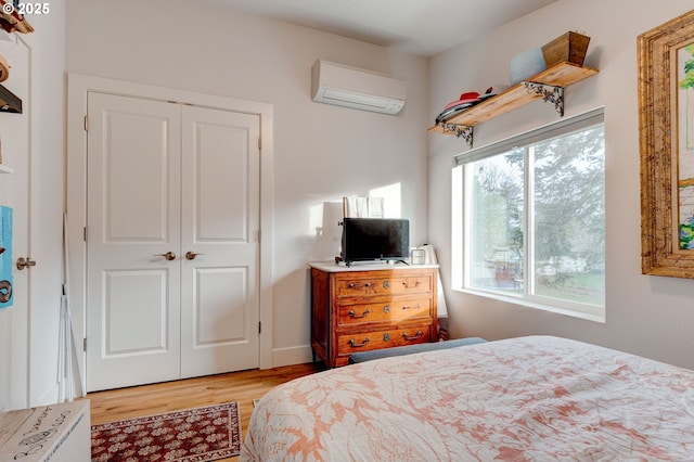 bedroom with light wood-type flooring, a closet, and a wall unit AC