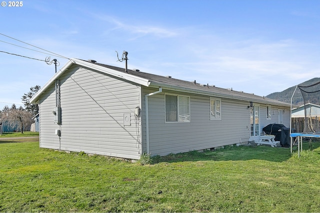 view of side of property featuring a trampoline and a lawn