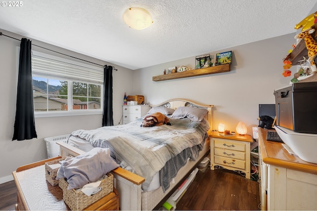 bedroom with wood finished floors, baseboards, and a textured ceiling