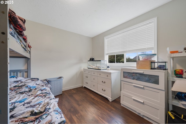 bedroom with dark wood finished floors, a textured ceiling, and baseboards