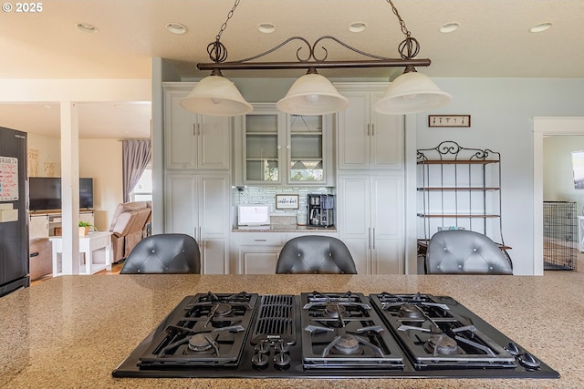 kitchen featuring black gas cooktop, decorative light fixtures, white cabinetry, tasteful backsplash, and glass insert cabinets