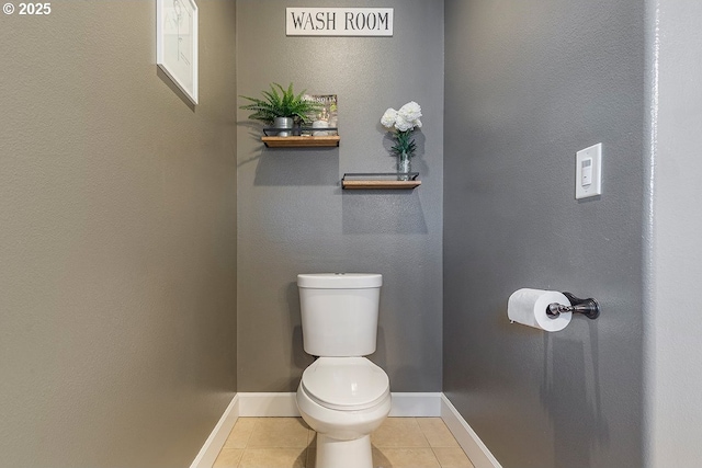 half bathroom with baseboards, toilet, and tile patterned floors