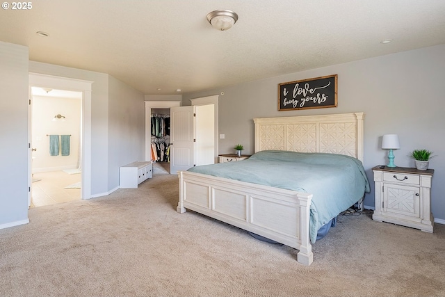 bedroom featuring ensuite bathroom, light carpet, baseboards, a spacious closet, and a closet