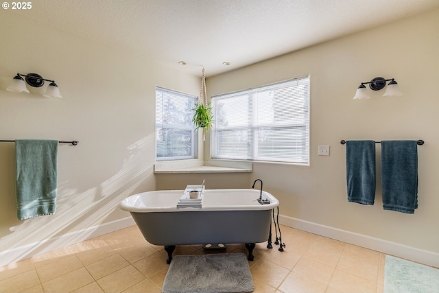 full bathroom with tile patterned flooring, a soaking tub, a textured ceiling, and baseboards