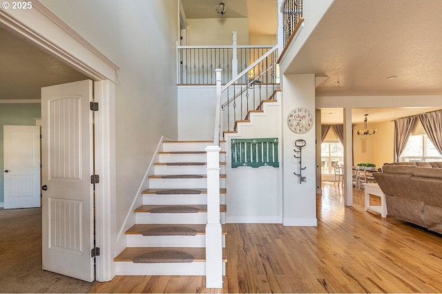 stairs featuring a notable chandelier, wood finished floors, and baseboards