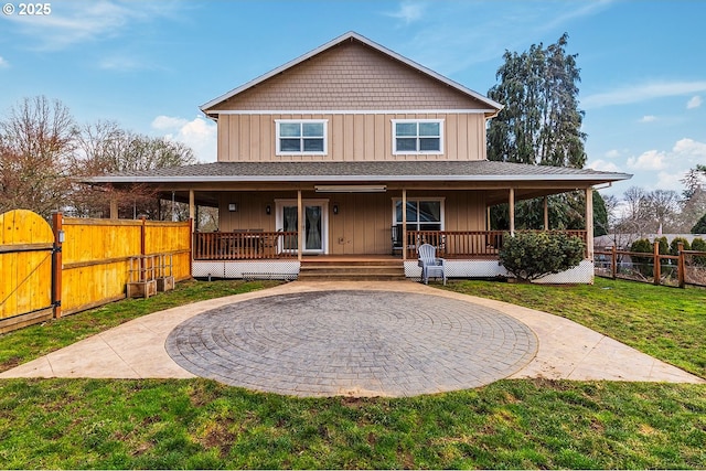 view of front facade featuring a porch, board and batten siding, a gate, fence, and a front lawn