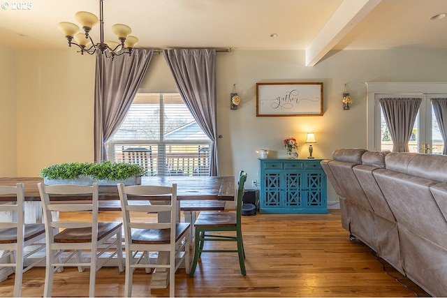 dining room featuring beamed ceiling, an inviting chandelier, and wood finished floors