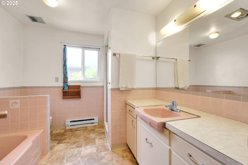 3310 Paula Ct, Eugene, OR 97404 - full bathroom featuring baseboard heating, tile walls, vanity, a garden tub, and a wainscoted wall