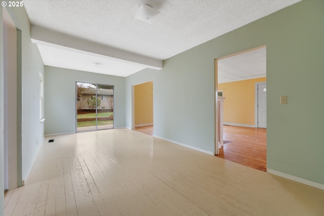 empty room with beamed ceiling, a textured ceiling, and light hardwood / wood-style flooring