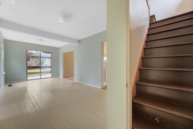 staircase featuring beamed ceiling, a textured ceiling, and hardwood / wood-style flooring