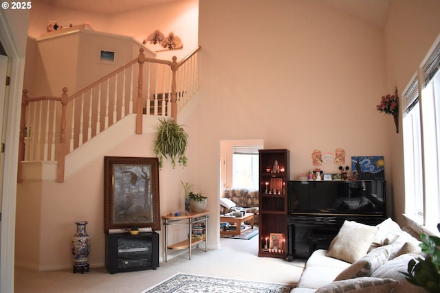 carpeted living room with stairs, a high ceiling, and plenty of natural light