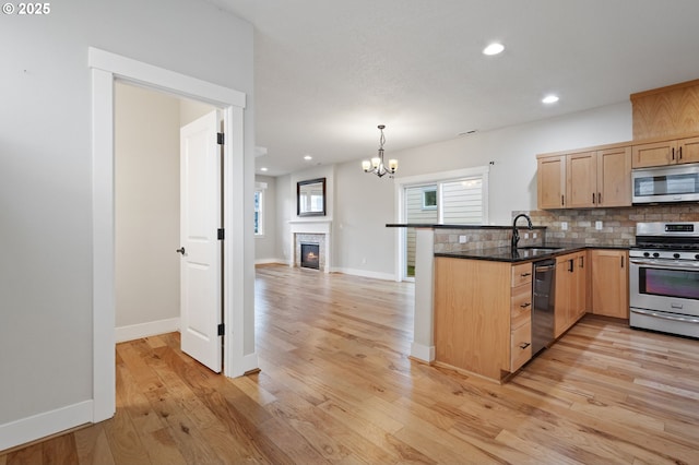 kitchen featuring appliances with stainless steel finishes, light brown cabinets, a peninsula, backsplash, and recessed lighting