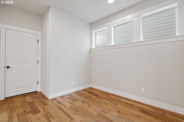 empty room with light wood-type flooring, baseboards, and recessed lighting