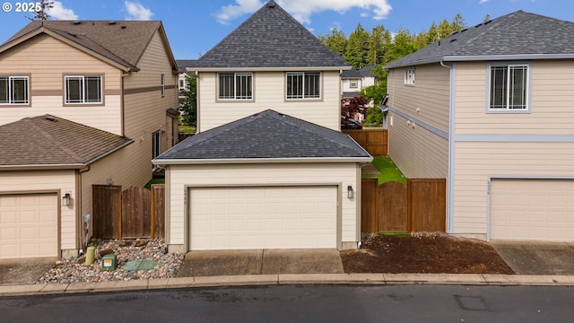 traditional-style home with roof with shingles, a garage, and fence