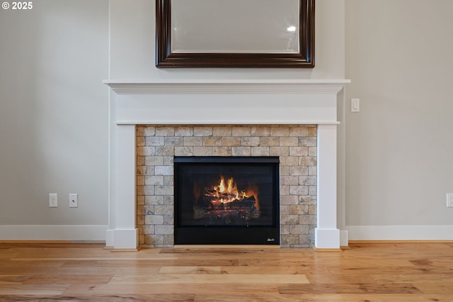 detailed view of a brick fireplace, wood finished floors, and baseboards