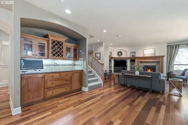 living room featuring recessed lighting, stairway, a stone fireplace, and light wood-style flooring