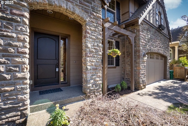 entrance to property with a garage, stone siding, and driveway