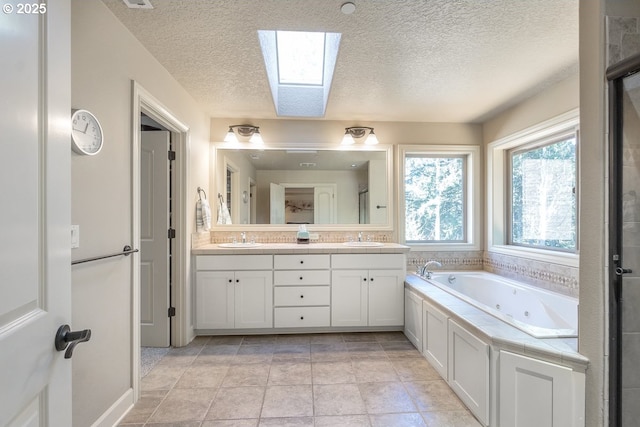 bathroom with a sink, double vanity, a skylight, and a whirlpool tub