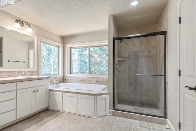 full bath with vanity, a stall shower, a textured ceiling, a garden tub, and tile patterned floors