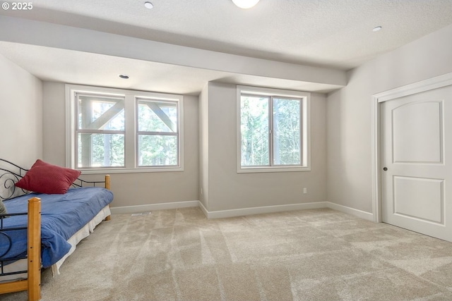 bedroom featuring baseboards, light carpet, and a textured ceiling