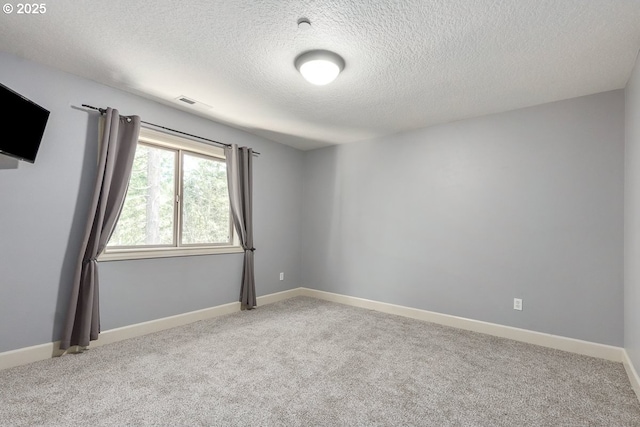 carpeted empty room with visible vents, a textured ceiling, and baseboards