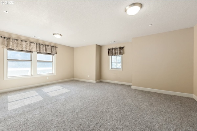 unfurnished room with visible vents, light colored carpet, a textured ceiling, and baseboards