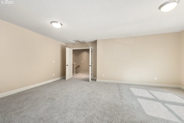 empty room with baseboards, a textured ceiling, and light carpet