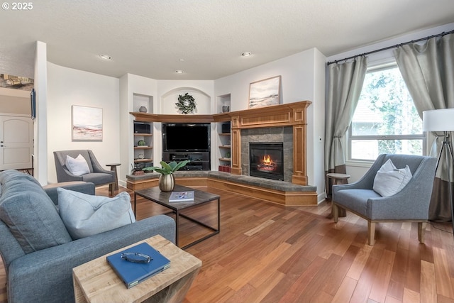 living room featuring a textured ceiling, wood finished floors, and a tiled fireplace