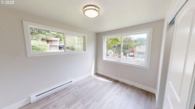 29700 Park Dr, Gold Beach, OR 97444 - unfurnished bedroom with a baseboard radiator, a closet, light wood finished floors, and baseboards