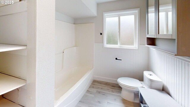 29700 Park Dr, Gold Beach, OR 97444 - bathroom featuring a wainscoted wall, wood finished floors, toilet, and tub / shower combination