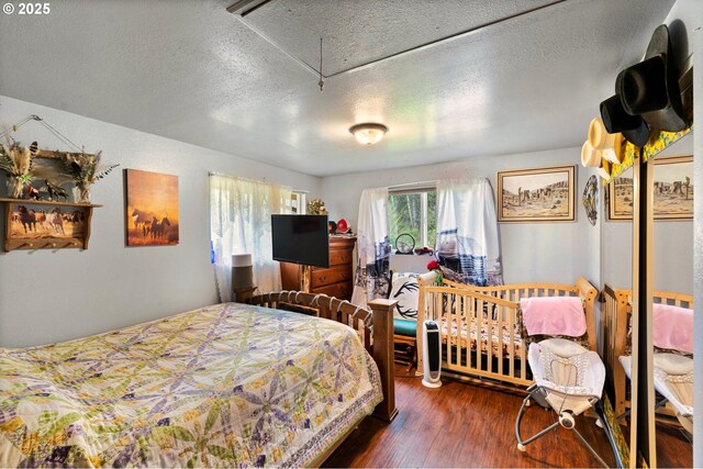 bedroom with attic access, a textured ceiling, and wood finished floors