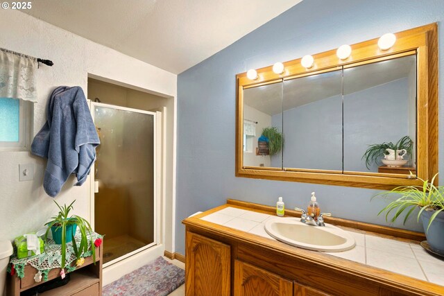bathroom featuring vanity, vaulted ceiling, tile patterned flooring, and a stall shower