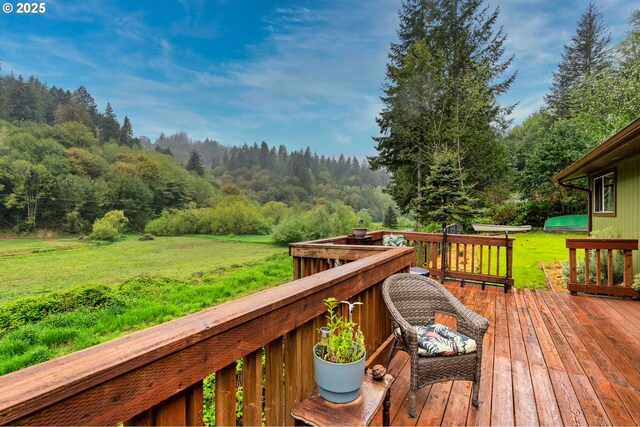 wooden terrace with a lawn and a wooded view
