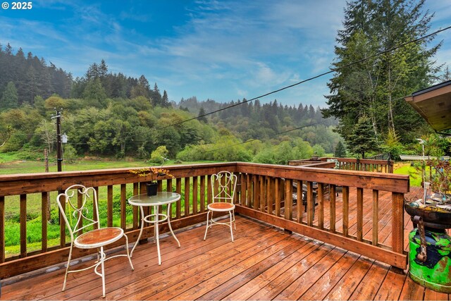 wooden terrace featuring a view of trees