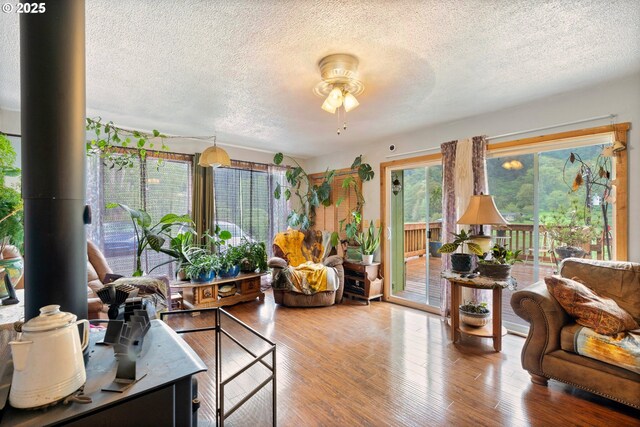 living area featuring a ceiling fan, a textured ceiling, and wood finished floors