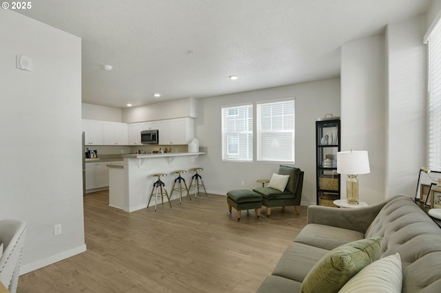 living room with light wood-style floors, baseboards, and recessed lighting