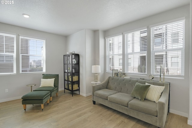 sitting room featuring light wood finished floors, baseboards, and a textured ceiling