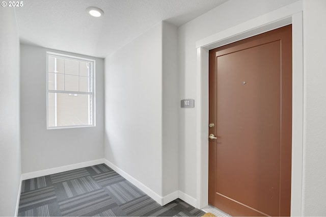 interior space featuring plenty of natural light, baseboards, dark colored carpet, and a textured ceiling